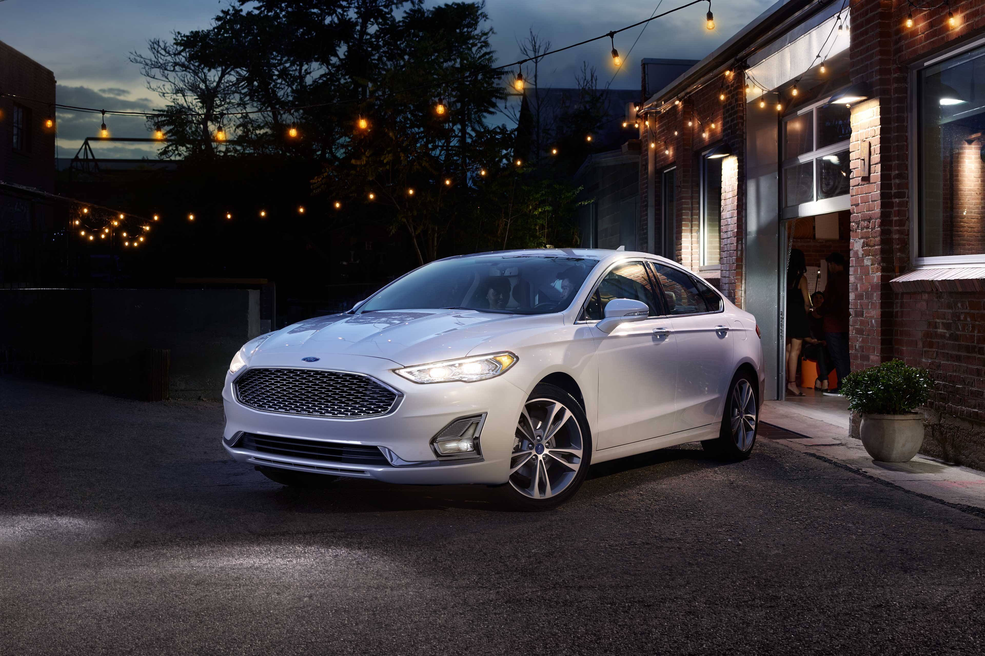 white 2019 ford fusion parked in front of a brick building at night