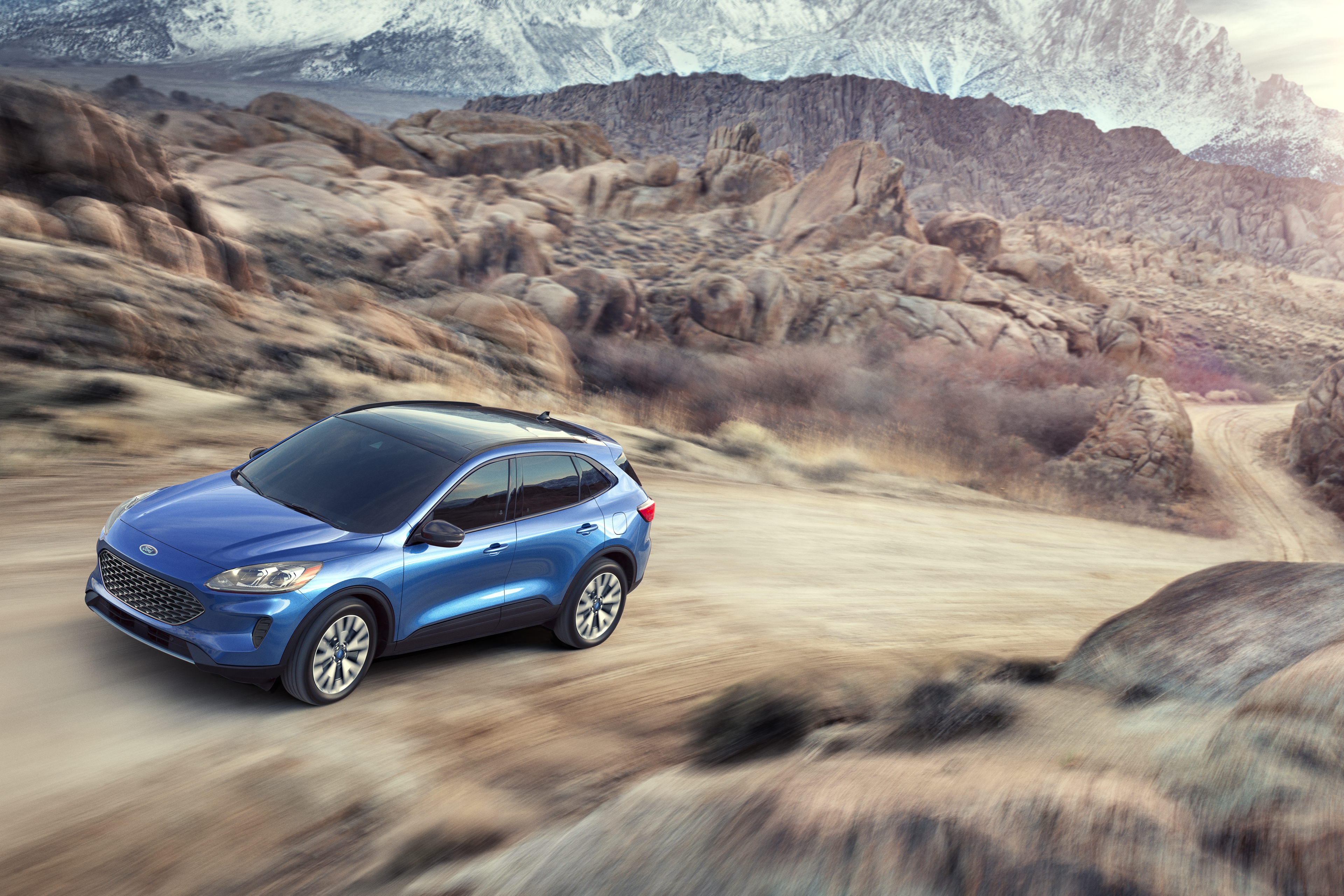 blue 2020 ford escape driving on a dirt path up a mountain