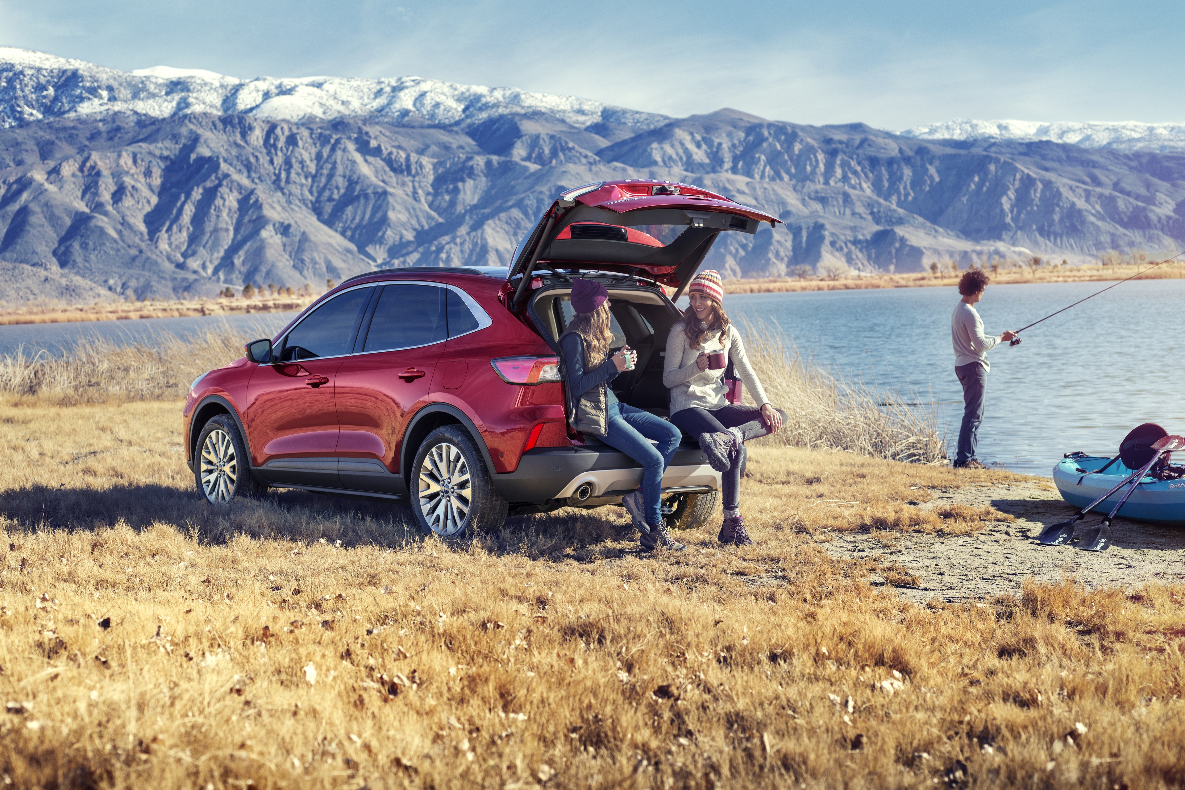 two girls talking while sitting on their red 220 ford escape next to a lake