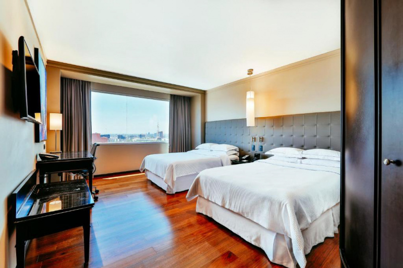 A guest room with 2 double beds, a desk and a city view.