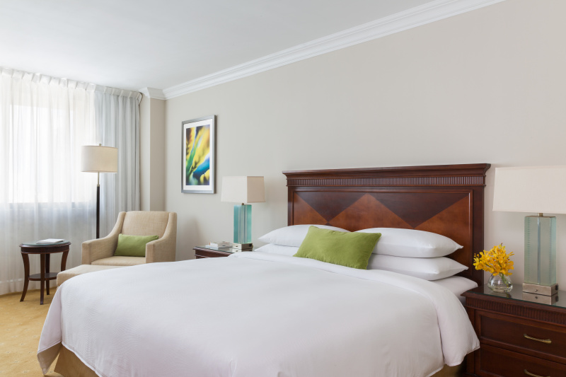 An accessible guest room with a carpeted floor, king-sized bed, bedside tables and an armchair.
