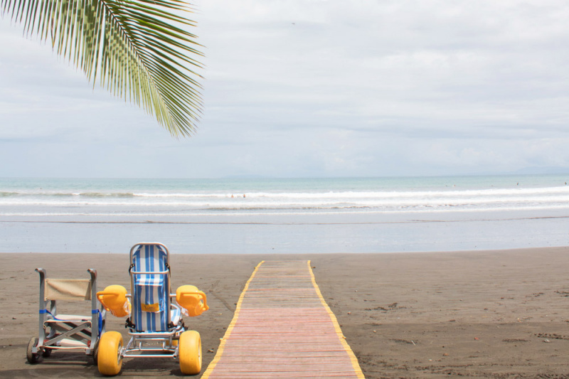 An amphibious chair sits next to an accessible pathway leading to Jaco Beach waters