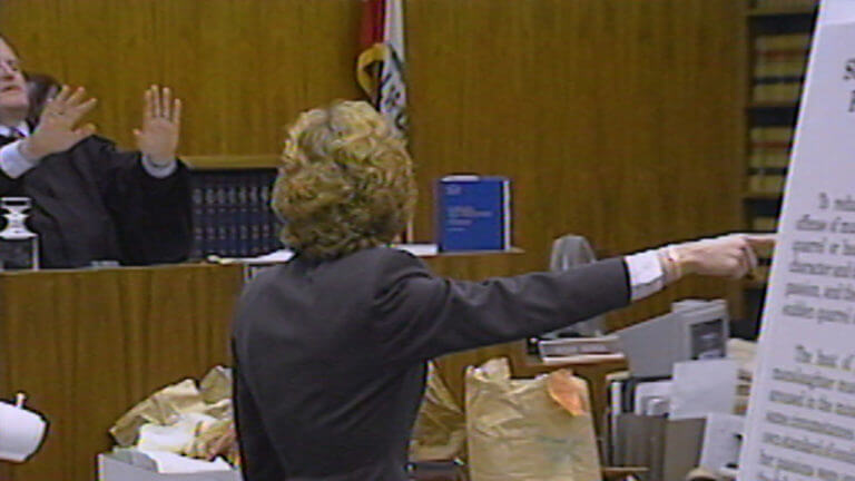 A woman points to a poster for the jury