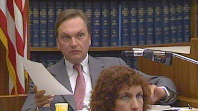 A man holds a piece of paper while testifying