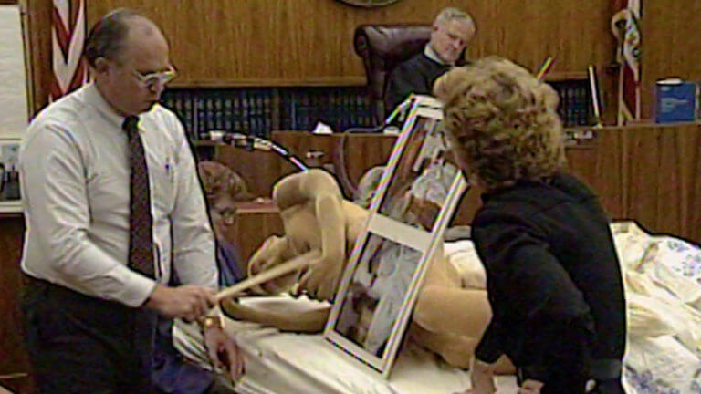 An attorney shows the jury a poster with photos.