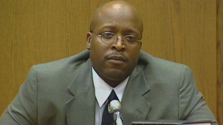 A man in a suit testifies in court.