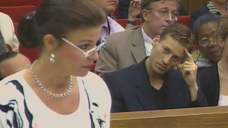 A woman with white glasses stands in court