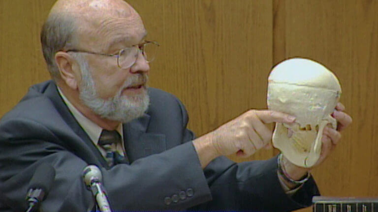 A man points to a model of a skull