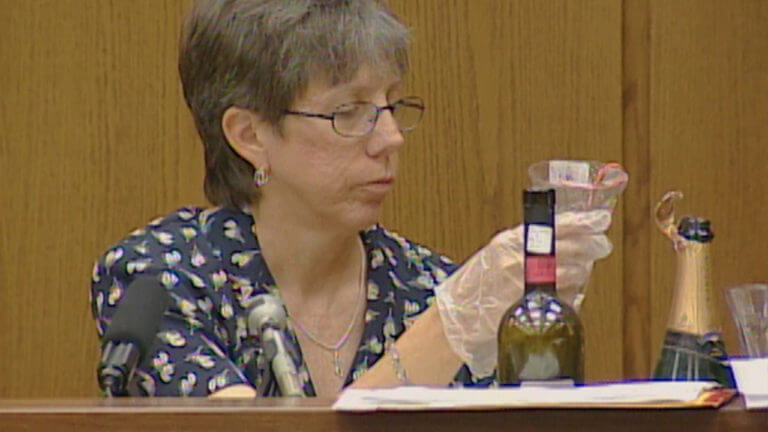 A woman wearing a glove holds up evidence