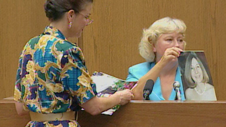 A woman holds up a photo for the jury