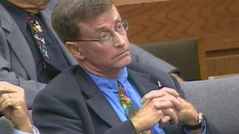 A man in a suit sits in court