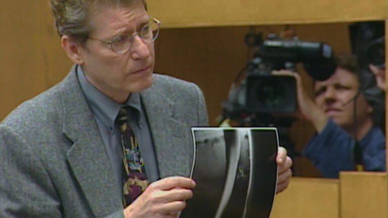 A man holds a photo for the jury