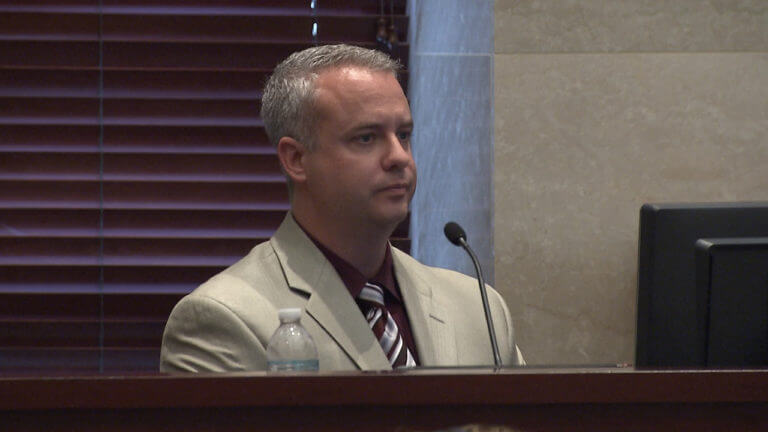 A man in a light jacket testifies in court