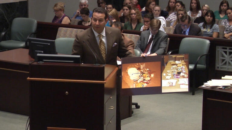 Jose Baez speaks from a podium