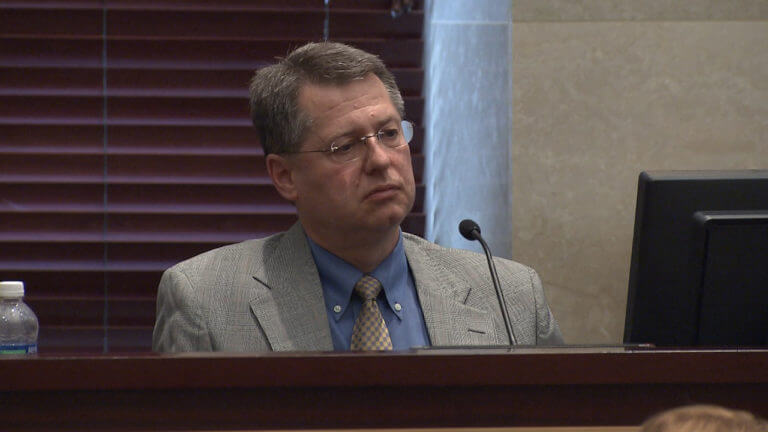 A man in a suit testifies in court.