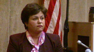 A woman wearing a scarf testifies in court