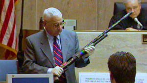 A man holds a long gun in court