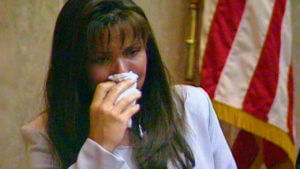 A woman holds a tissue to her face