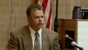 A man in a suit testifies in court.