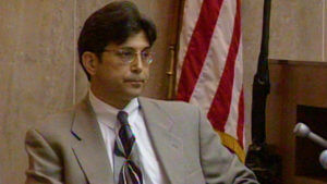 A man in a suit testifies in court.