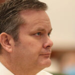 A profile view of a man sitting in court