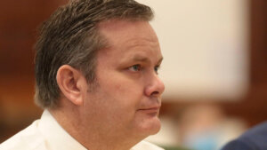 A profile view of a man sitting in court