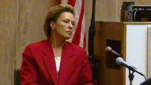 A woman in a red blazer testifies in court