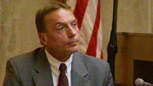 A man in a suit sits in court