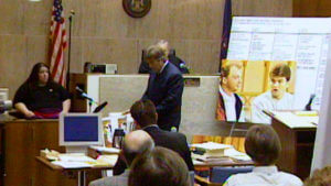 An attorney stands in a crowded courtroom