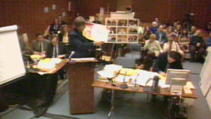 A person speaks at a podium in a courtroom