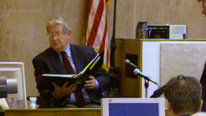 A witness holds a book open in court