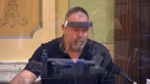 a man testifies wearing a face shield