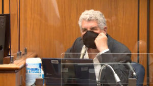 A person testifies while wearing a face mask