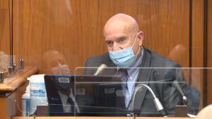 a man wears a face mask while testifying