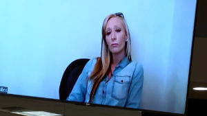 a woman is seen sitting against a white wall