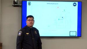 police officer stands next to projection screen