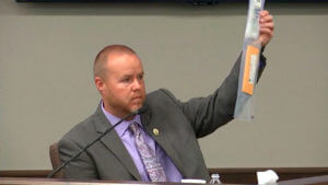 Man holds up evidence in court from witness stand