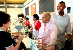 A customer picks up some food to-go from Sweetie Pie's owner Robbie Montgomery, center, and Montgomery's son, James 