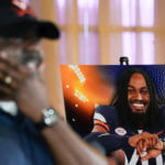 A man wipes away tears with a photo of a football player in the background