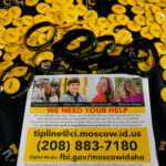 A flyer seeking information about the killings of four University of Idaho students who were found dead is displayed on a table along with buttons and bracelets