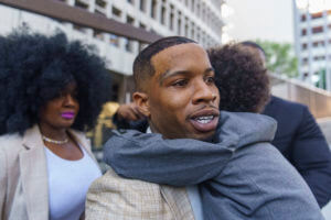 Tory Lanez walks out of a courthouse with a child around his neck