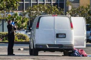 A forensic photographer takes pictures of a van's window and its contents in Torrance, Calif., Sunday, Jan. 22