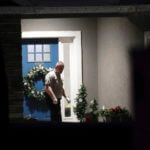 A law enforcement official stands near the front door of the Enoch, Utah, home where eight family members were found dead