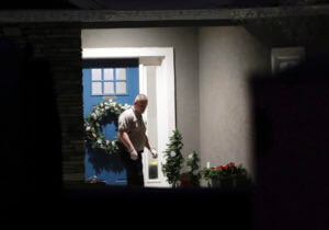 A law enforcement official stands near the front door of the Enoch, Utah, home where eight family members were found dead