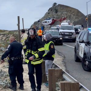 emergency personnel respond to a vehicle over the side of Highway 1 on Jan. 1, 2023, in San Mateo County