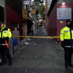 Police officers stand guard at the scene where dozens of people died and were injured during a crowd surge in Seoul