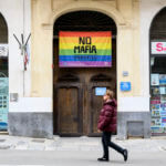 A man walks past a flag that reads: 