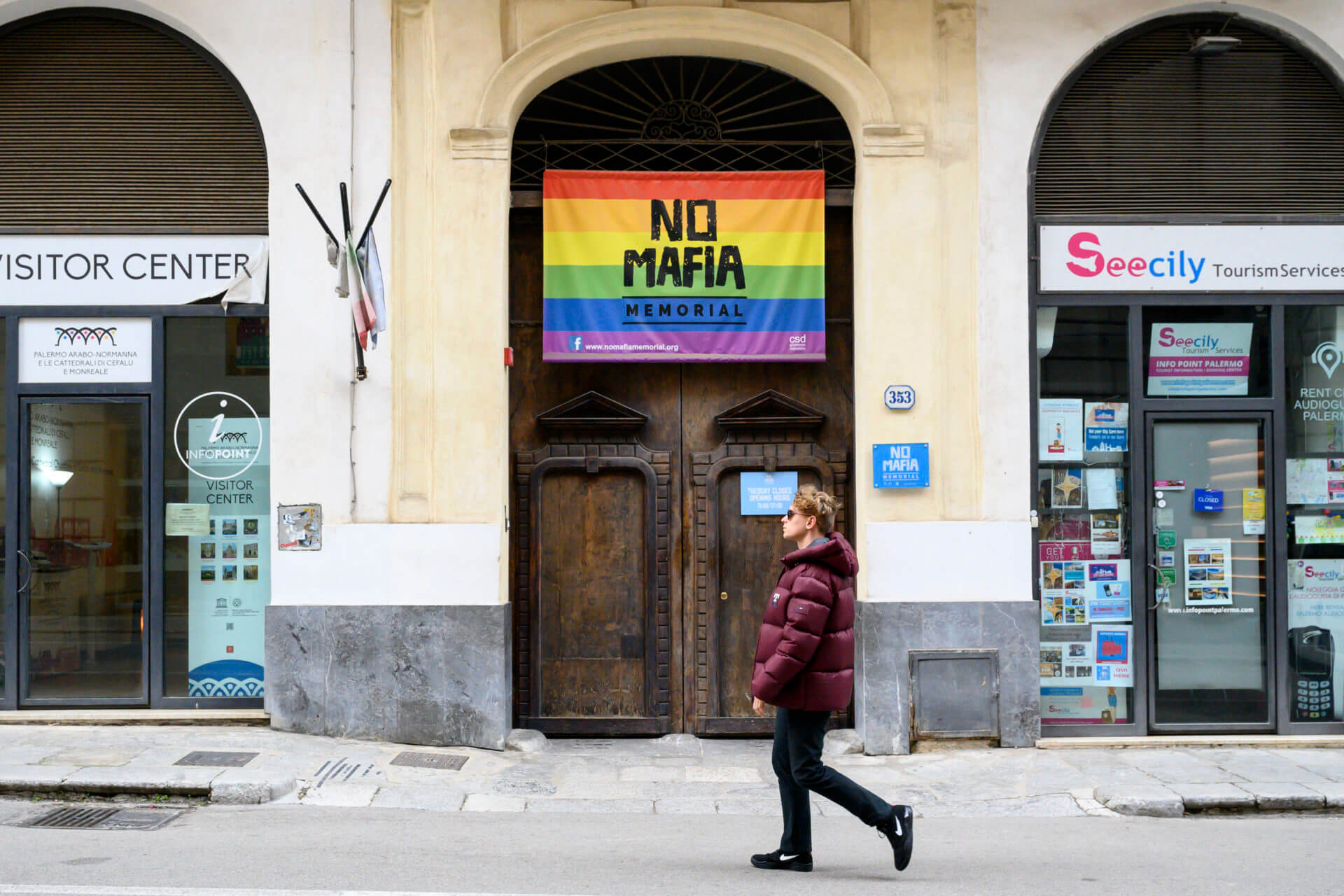 A man walks past a flag that reads: 