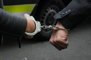 Police officers escort Andrew Tate, left, handcuffed to his brother Tristan