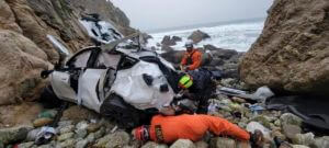 emergency personnel respond to a vehicle over the side of Highway 1 on Jan. 1, 2023, in San Mateo County